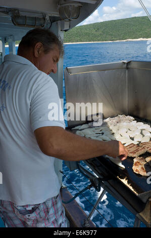 Prepairing pesce per pranzo in una giornata turistica in barca di Mali Losinj, isola di Losinj Croazia Foto Stock