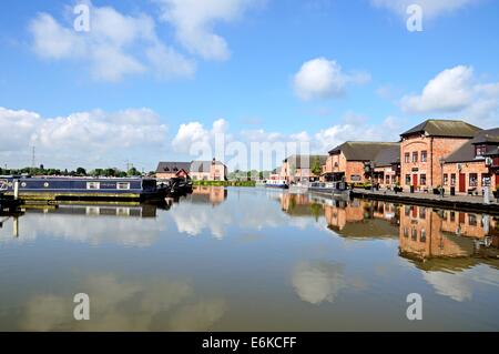 Narrowboats ormeggiati davanti a bar, negozi e ristoranti nel bacino del canale, Barton Marina, Barton-sotto-Needwood, England, Regno Unito Foto Stock