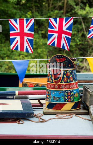 Canal arte popolare caraffe di metallo sul tetto di un narrowboat con union jack flag bunting sul Grand Union Canal Foto Stock