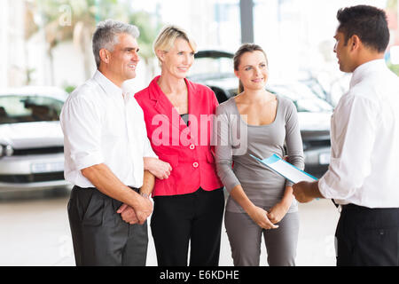 Venditore auto a parlare di famiglia in showroom Foto Stock