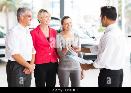 Gentile Venditore consegna chiave auto al cliente in showroom Foto Stock