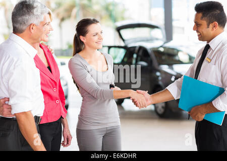 Veicolo handshaking venditore con i giovani adulti il cliente dopo la vendita Foto Stock