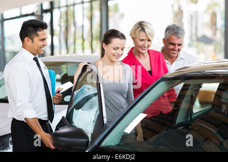 Bello Venditore auto che mostra una nuova vettura per una famiglia Foto Stock