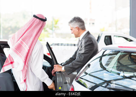 Uomo arabo per entrare in una nuova vettura per test drive presso la concessionaria del veicolo Foto Stock