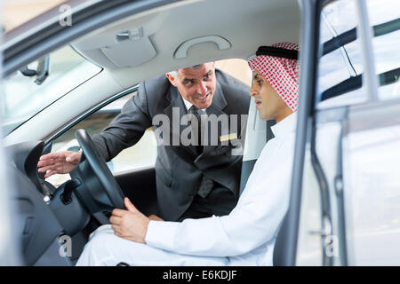 Gentile Venditore senior per spiegare le funzioni auto per uomo arabo Foto Stock