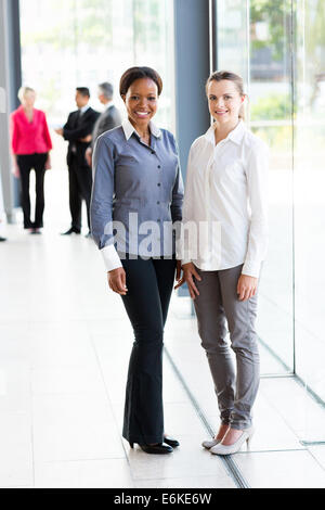 Due belle multirazziale donne business in piedi in ufficio Foto Stock