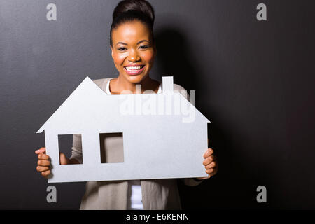 Splendida donna africana tenendo premuto il simbolo home isolato su sfondo nero Foto Stock