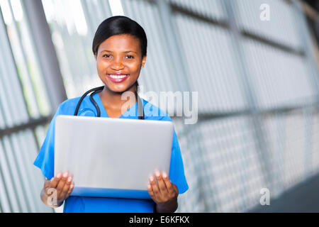 Professional americano africano medico donna tenendo il computer portatile Foto Stock