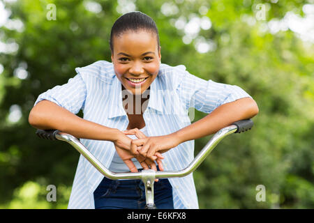 Ritratto di felice ragazza africana su una bici in foresta Foto Stock