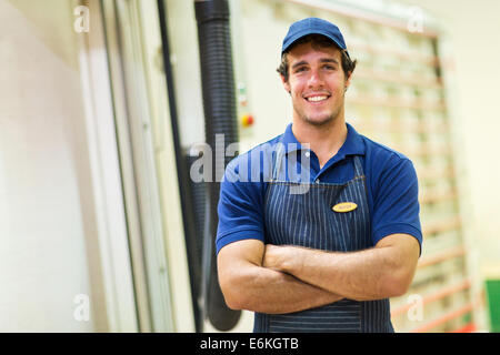 Falegname sorridente in piedi in officina Foto Stock