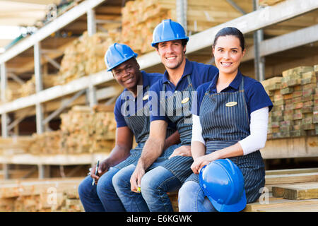 Il gruppo di allegro giovane negozio di ferramenta co-lavoratori in appoggio al legname Foto Stock