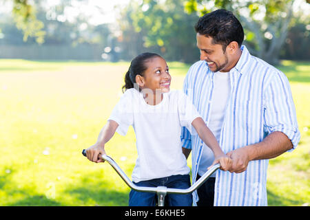 Indiano amorevole padre figlia di insegnamento per un giro in bicicletta nel parco Foto Stock