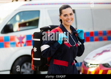 Bella giovane femmina paramedico che trasportano lifepack davanti ambulanza Foto Stock