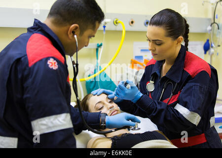 I paramedici esame paziente femmina in ospedale Foto Stock