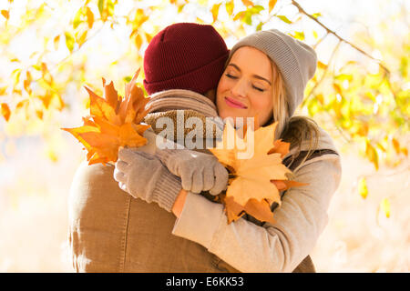 Bella giovane donna abbracciando il fidanzato in autunno Foto Stock