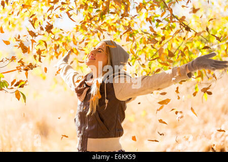 In autunno le foglie che cadono sulla felice giovane donna nella foresta Foto Stock