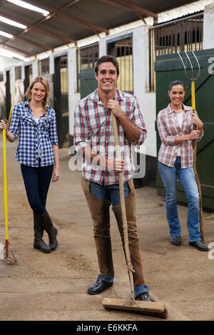 Gruppo di lavoratori agricoli con strumenti in stabile Foto Stock