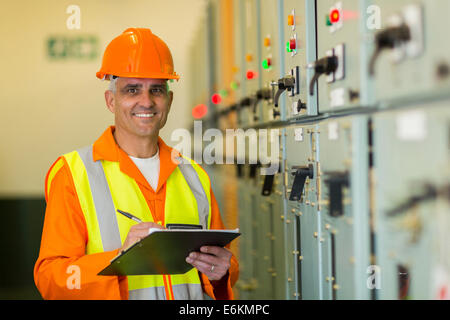 Ritratto di sorridente elettricista maturo lavorando nella sala di controllo Foto Stock