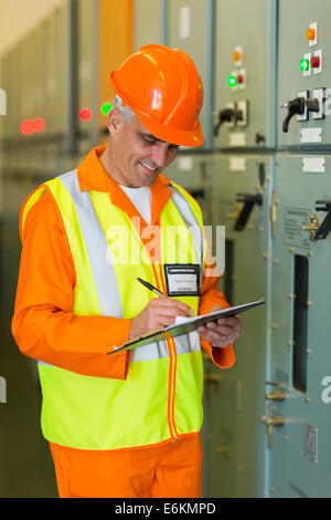 Senior tecnico industriale tenendo la macchina letture in sala di controllo Foto Stock