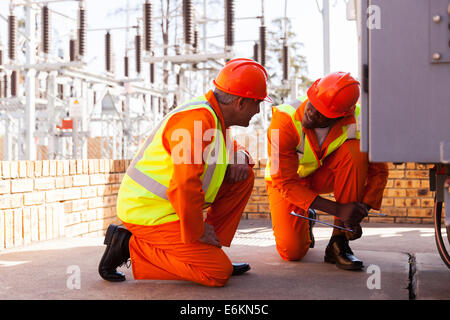 Due esperti elettricisti a discutere di lavorare nella sottostazione elettrica Foto Stock