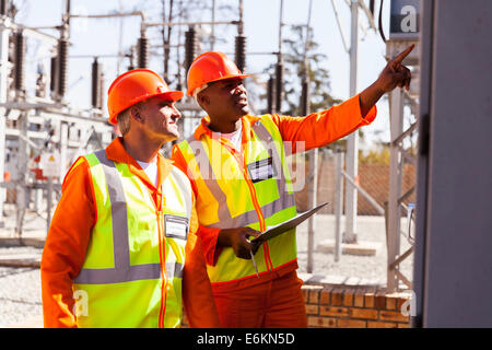 Il successo degli ingegneri elettrici prendendo letture macchina nella sottostazione Foto Stock