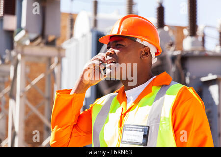 African ingegnere elettrico tramite telefono cellulare nella sottostazione Foto Stock