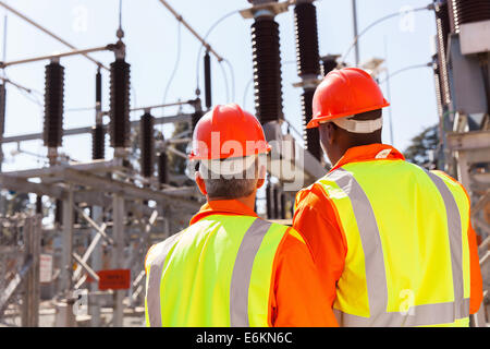 Vista posteriore di due ingegneri elettrici nella sottostazione Foto Stock