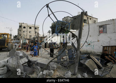 Rafah nella striscia di Gaza, Territori palestinesi. 26 Ago, 2014. Bambini palestinesi gioco intorno a un distrutto mini ruota panoramica nei pressi dei resti di case che sono state distrutte da un attacco aereo israeliano a Rafah cittadina nel sud della striscia di Gaza il 26 agosto 2014. Fuoco israeliano uccisi 10 palestinesi di fronte a Gaza il 25 agosto, mentre l'Egitto ha proposto un nuovo cessate il fuoco che avrebbe aperto passaggi chiave nel territorio bloccato. Credito: ZUMA Press, Inc./Alamy Live News Foto Stock