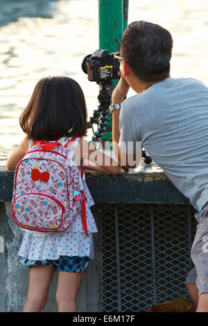 Padre e figlia. L'uomo, piccola ragazza e la fotocamera su un treppiede in Causeway Bay Hong Kong. Foto Stock