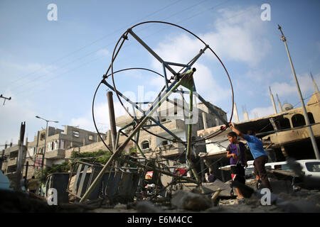 Rafah nella striscia di Gaza. 26 Ago, 2014. Bambini palestinesi gioco intorno a un distrutto mini ruota panoramica nei pressi dei resti di case che sono state distrutte da un attacco aereo israeliano a Rafah cittadina nel sud della striscia di Gaza. Fuoco israeliano uccisi 10 palestinesi attraverso la striscia di Gaza, mentre l'Egitto ha proposto un nuovo cessate il fuoco che avrebbe aperto passaggi chiave nel territorio bloccato. Credito: Ibrahim Khatib/Pacific Press/Alamy Live News Foto Stock