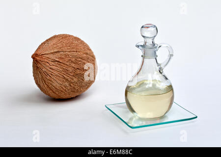 Olio di noce di cocco nella caraffa di vetro, tutta la noce di cocco. Foto Stock