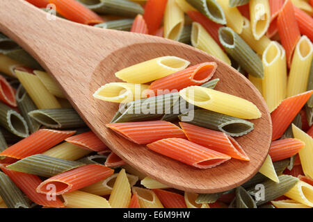 Penne rigate pasta in un cucchiaio di legno su penne rigate pasta dello sfondo. Primo piano. Foto Stock