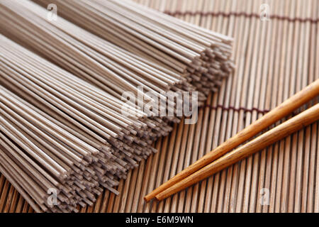 Materie soba noodles e bacchette sul tovagliolo di bambù. Soba è un tipo di sottile a base di noodle giapponesi realizzati da farina di grano saraceno. Primo piano. Foto Stock