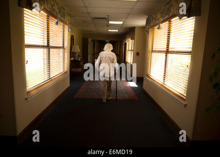 Donna anziana a piedi attraverso il corridoio Foto Stock