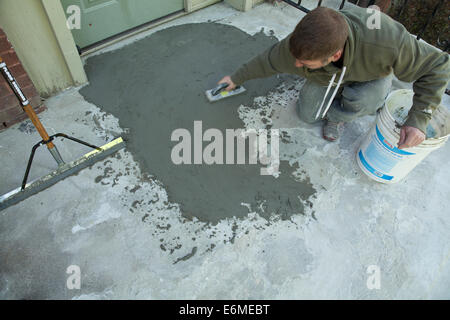 Workman smussa un rivestimento skim di cemento su una vecchia scalinata. Foto Stock