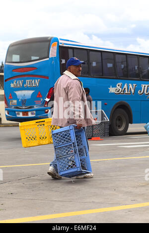 AMBATO, ECUADOR - 12 Maggio 2014: persona non identificata che trasportano le casse di plastica sull'area del terminal degli autobus Foto Stock