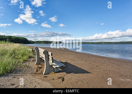 Un vecchio cemento e legno banco a Sandy Point Beach rivolto verso il fiume Penobscot in Stockton molle, Maine Foto Stock