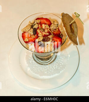 Yogurt con fragole, mirtilli e dadi, guarnita con tutto il grano bagel chip. Foto Stock