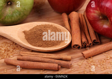 Torta di mele ingredienti. Mele, bastoncini di cannella, cannella in polvere in un cucchiaio di legno e marrone e zucchero di canna. Primo piano. Foto Stock