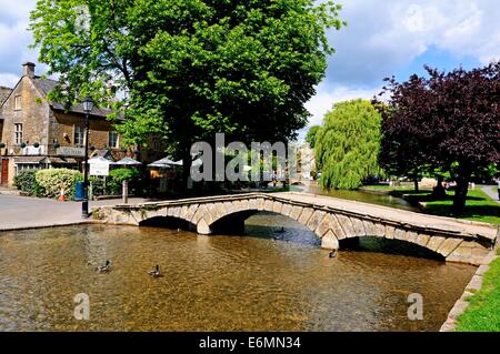 Passerella di pietra al di là del Fiume Windrush con sale da tè al posteriore, Bourton sull'acqua, Gloucestershire, Inghilterra, Regno Unito. Foto Stock