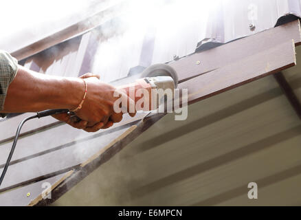 Lavoratore utilizzare piccolo utensile di molatura per il taglio di legno da costruzione Foto Stock