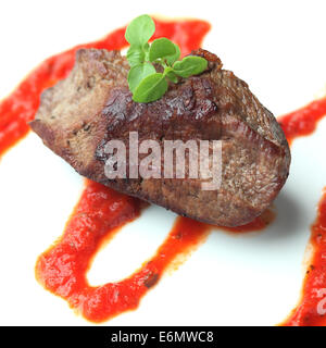 Arrosto di manzo con salsa di pomodoro e basilico. Sfondo bianco. Close-up. Foto Stock