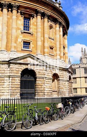 Biciclette appoggiata contro le ringhiere con Radcliffe Camera alla parte posteriore, Oxford, Oxfordshire, Inghilterra, Regno Unito, Europa occidentale. Foto Stock