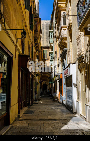 In legno tipico ed ornato dei balconi in ferro sopra il display shop windows in una strada stretta che porta ad un ombreggiato corridoio arcuato Foto Stock