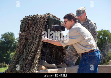 Un US Army istruttore con il Texas Guardia nazionale, spiega l'avanzato sistema di puntamento al governatore del Texas Rick Perry durante una visita a Camp Swift Agosto 13, 2014 in Bastrop, Texas. Perry ha distribuito il Texas Guardia Nazionale dal confine con il Messico a sostegno del funzionamento di sicurezza forti. Foto Stock