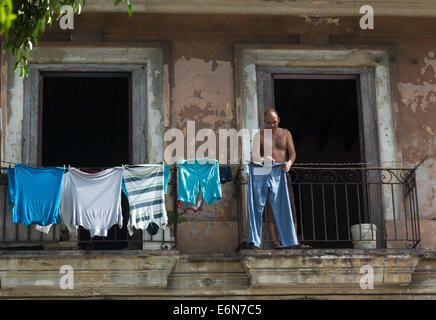 Uomo con lavanderia sul balcone, Central Havana, Cuba Foto Stock