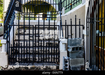 Scale dietro una cancellata in ferro battuto che conduce ad un portico su una casa in Frederiksted, St. Croix, U. S. Isole Vergini. Foto Stock