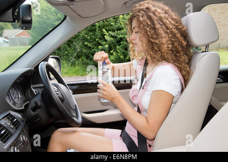 Giovani driver femminile di togliere il tappo da una bottiglia di acqua potabile Foto Stock