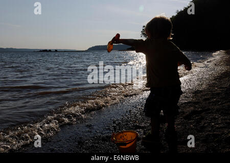 Un giovane ragazzo giocando con una benna e vanga sulla spiaggia, Plage Jacques Cartier, Quebec sul San Lorenzo Riva Foto Stock