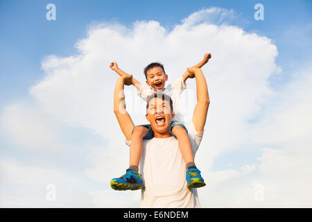 Felice piccolo ragazzo seduto sul padre della spalla Foto Stock